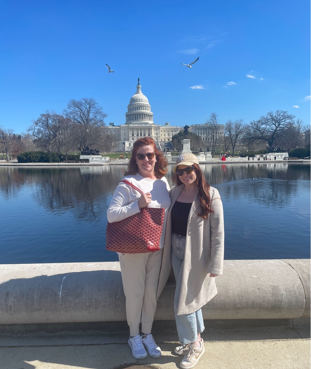Two women standing next to each other in front of a body of water
Description automatically generated