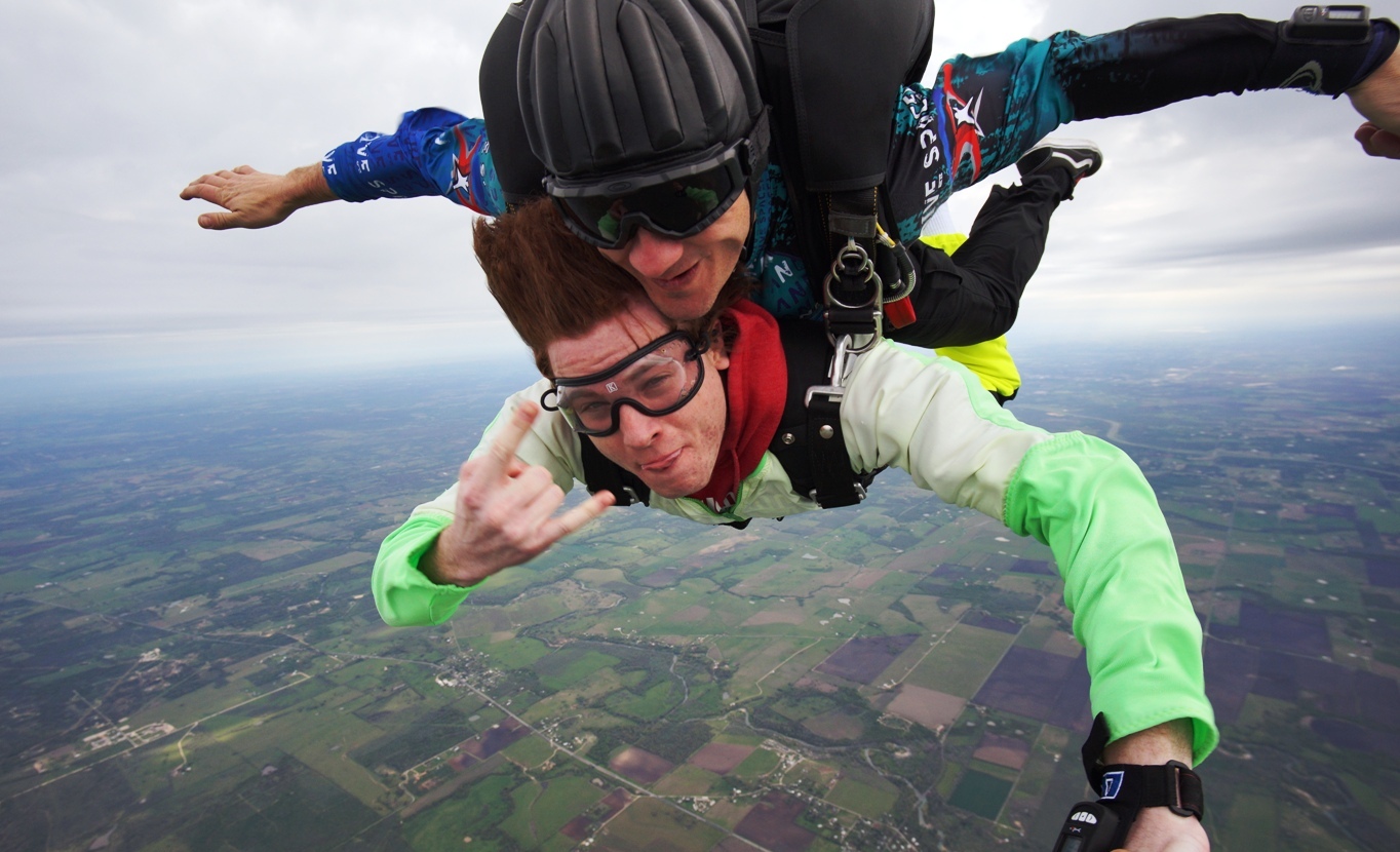 A person skydiving with another person in the sky

Description automatically generated