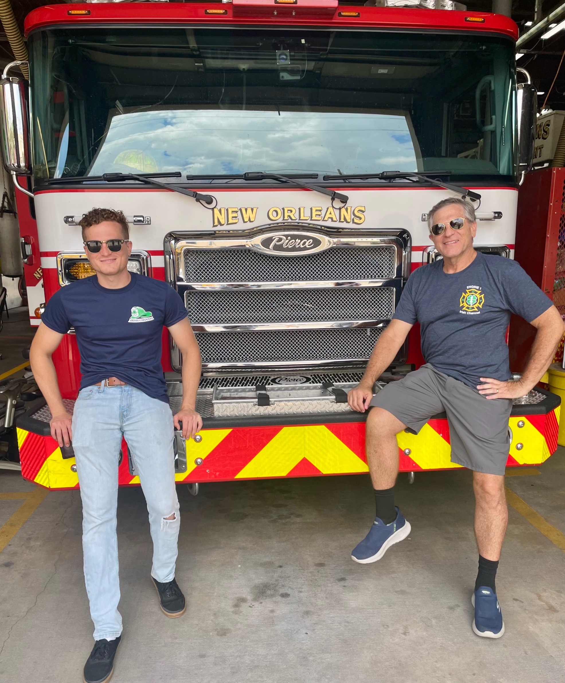 Two men posing for a picture in front of a fire truck
Description automatically generated