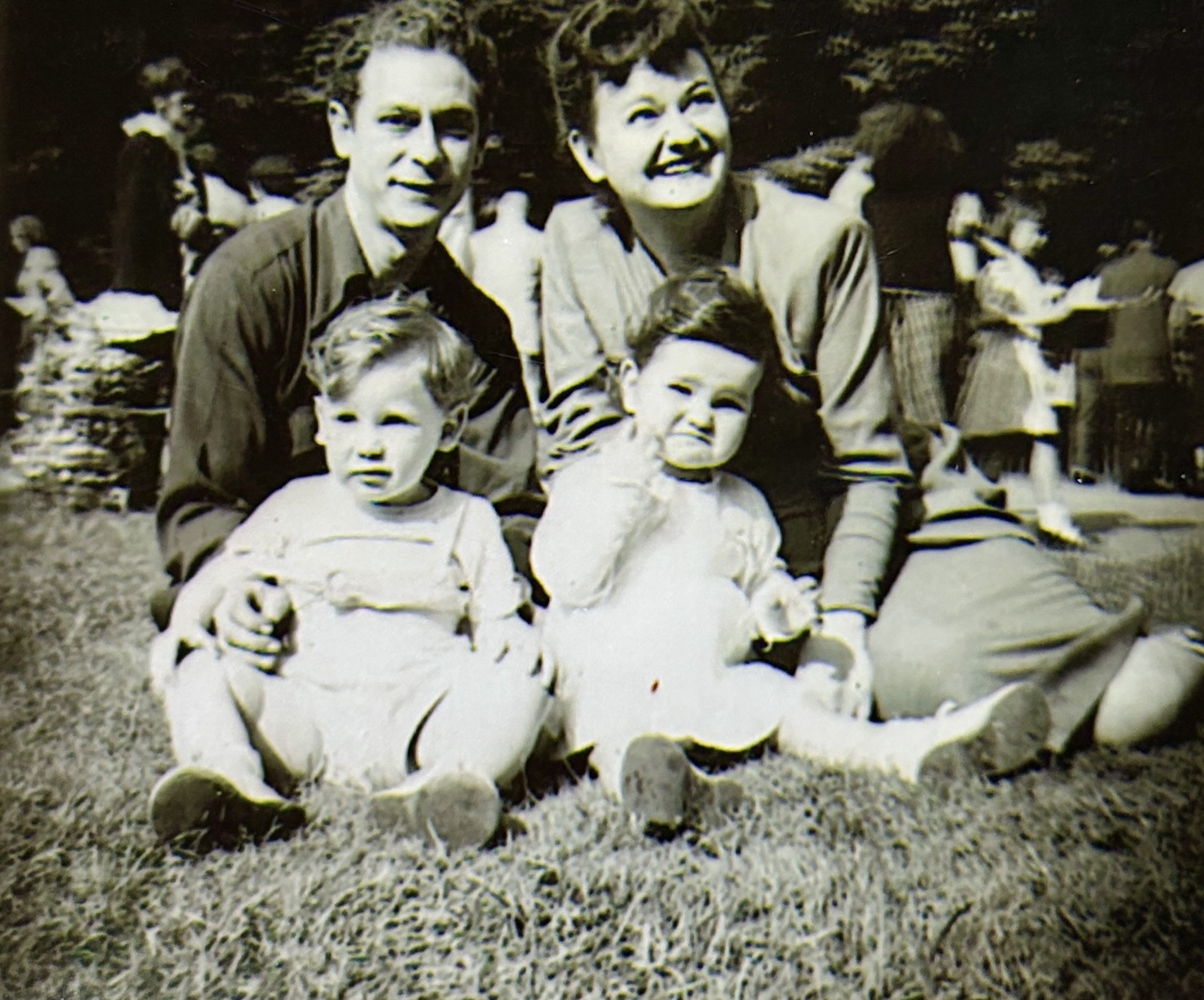 A family sitting on the grass

Description automatically generated