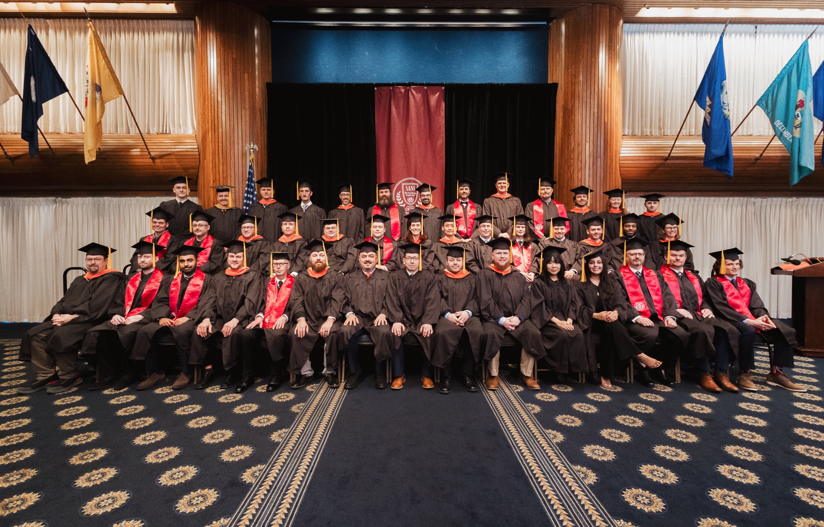A group of graduates in brown gowns and caps

Description automatically generated