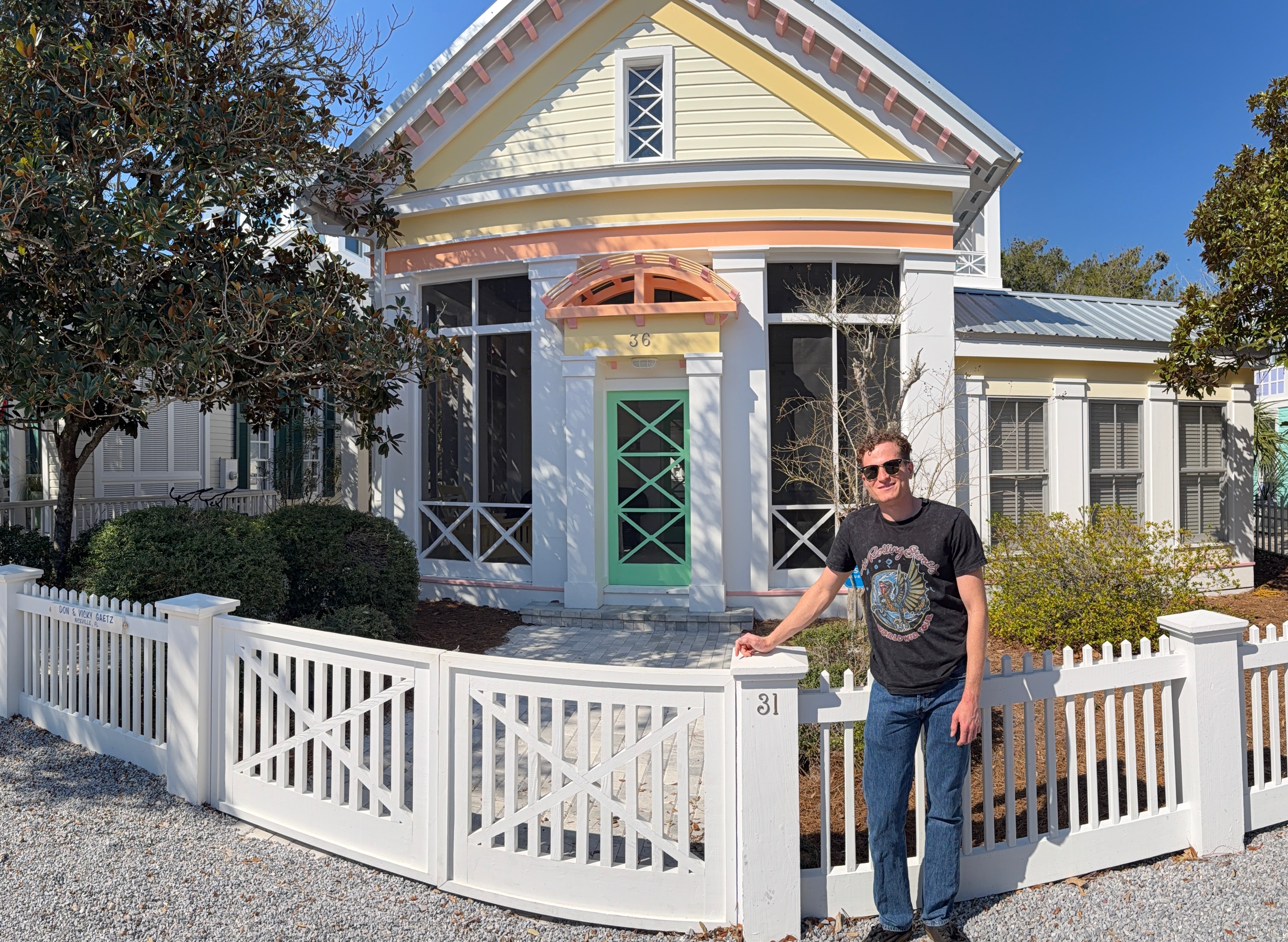A person standing in front of a white fence in front of a house

Description automatically generated