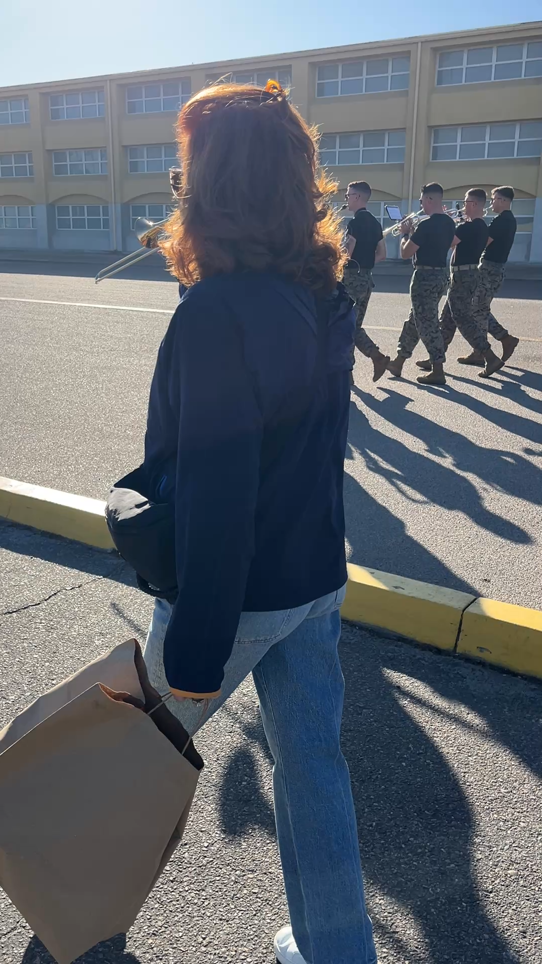 A person walking in a street with soldiers behind her
Description automatically generated