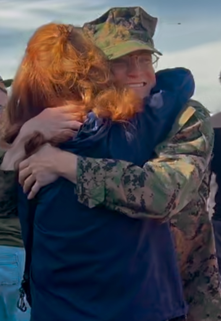 A person in military uniform hugging a person
Description automatically generated