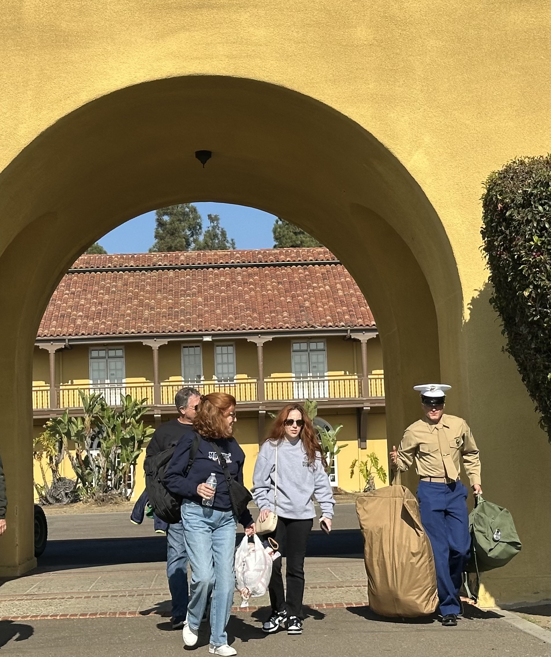 A group of people walking under a yellow archway
Description automatically generated